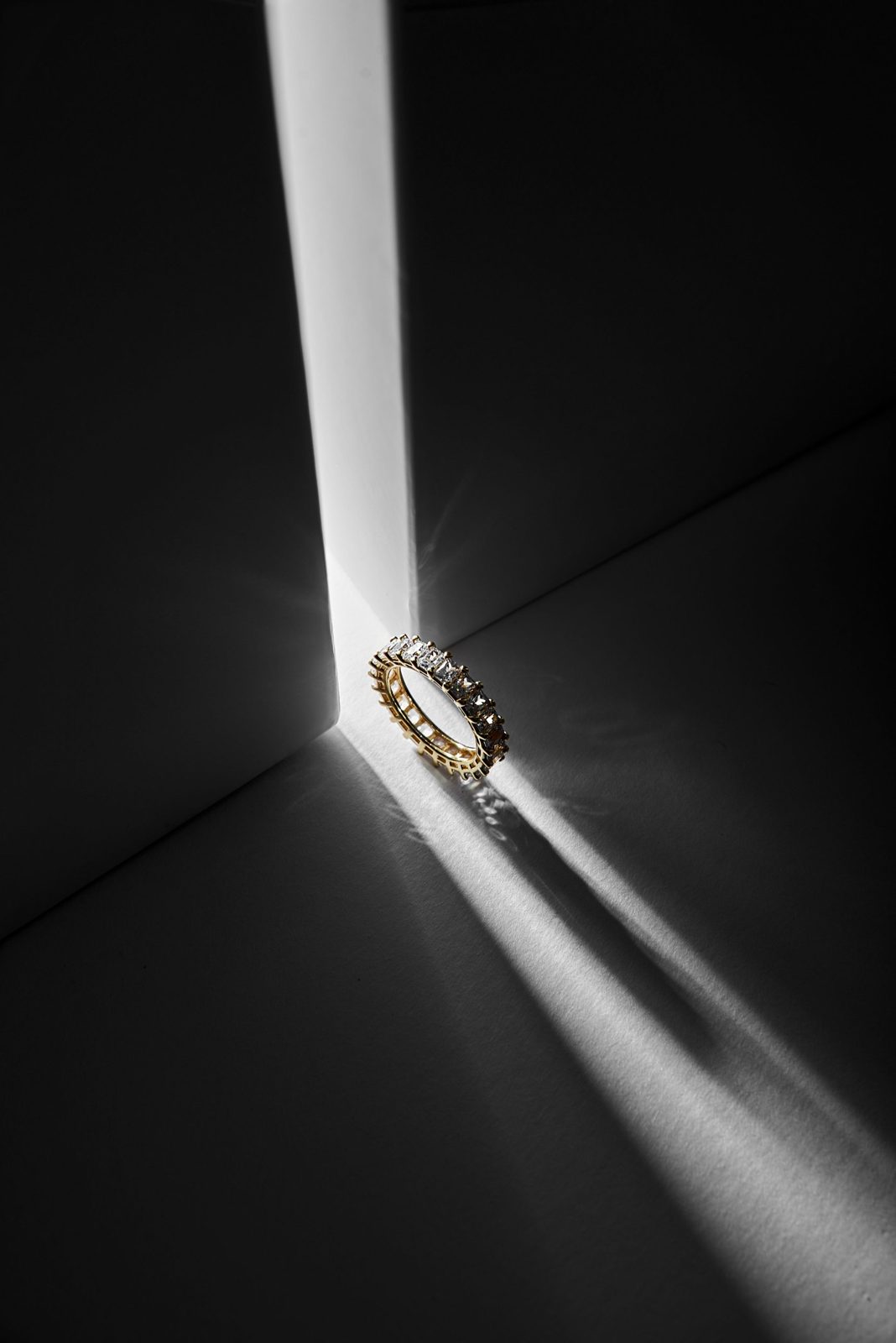 A gold diamond eternity band caught in a beam of light